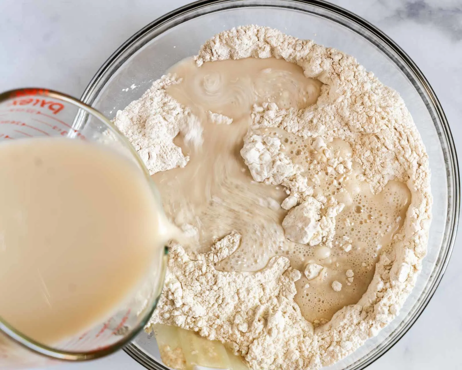 Bread starter and water added to flour in a bowl to make sourdough.