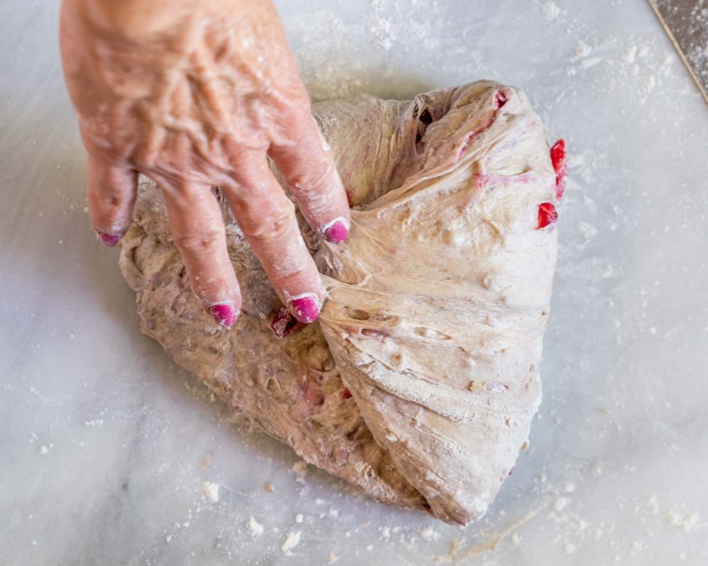 Image showing the right side of dough stretched to the left in order to shape a loaf of sourdough.