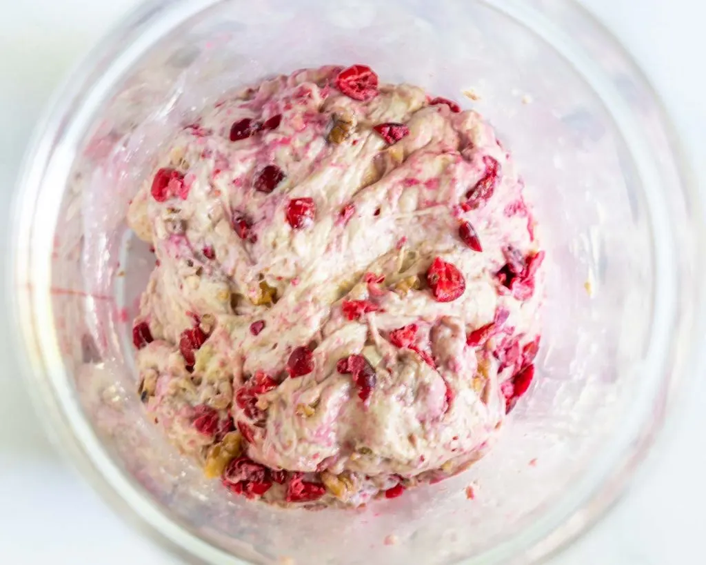 Cranberries and walnuts added to sourdough in a bowl.