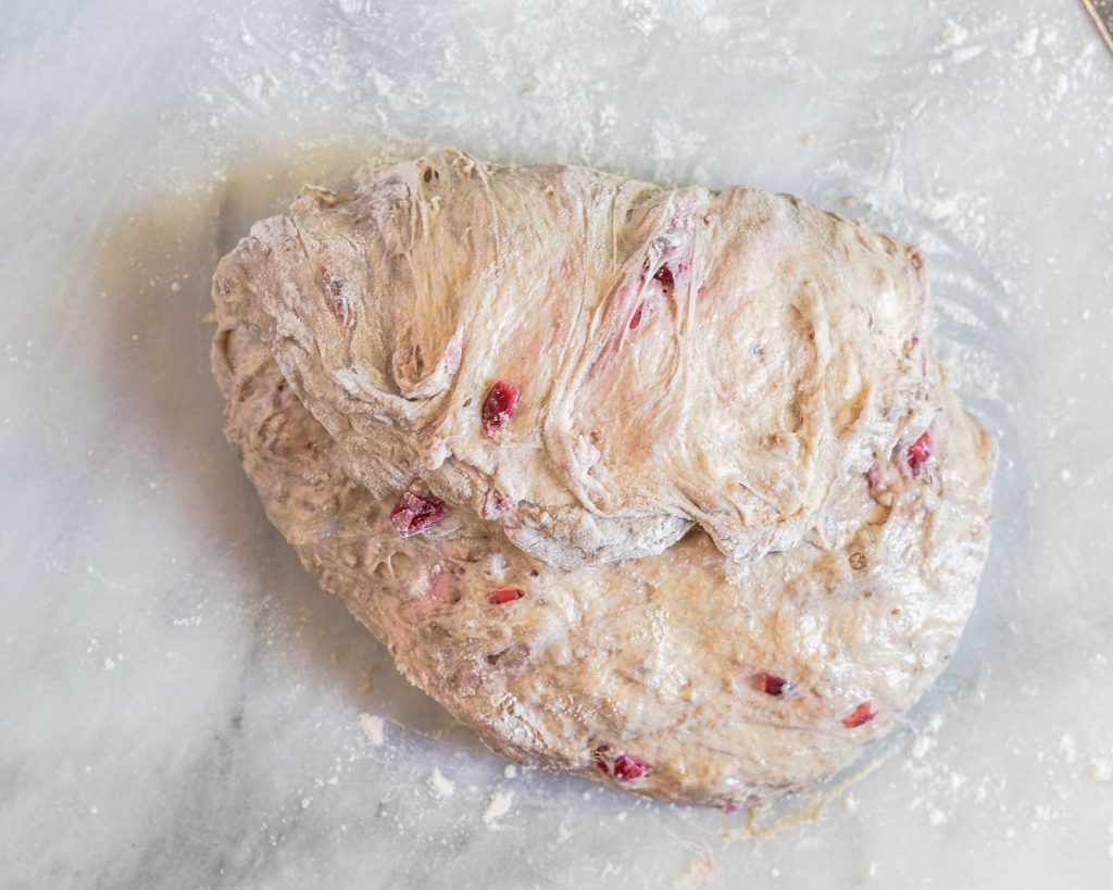 Image showing the top half of dough stretched to the bottom half in order to shape a loaf of sourdough.