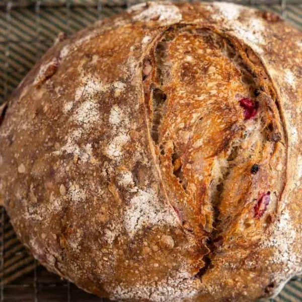 Top down view of a loaf of sourdough filled with cranberries and walnuts.