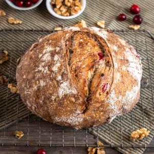 Top angled view of a baked loaf of sourdough walnut cranberry bread.