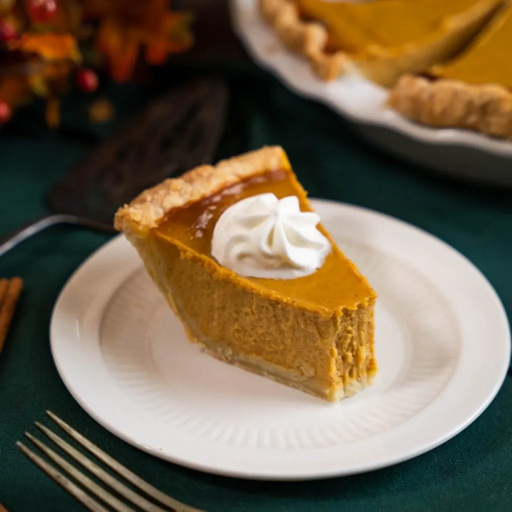 Slice of perfect pumpkin pie dessert with a bite taken out of it.