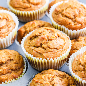 Close up view of pumpkin and banana muffins sitting on a muffin tin.