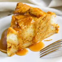 A slice of pumpkin pie instant pot bread pudding on a plate with a fork sitting on it.