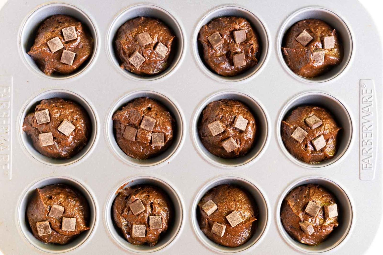 Top down view of a muffin tin filled Chocolate Chip Pumpkin Muffin Recipe batter