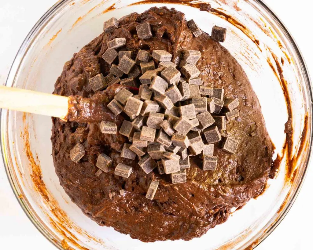 Top down view of Chocolate muffin batter topped with chunks of chocolate.