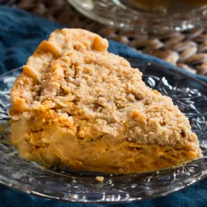 A slice of pie with punkin filling under a layer of streusel.