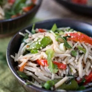 Angled view of asian noodle salad with crisp vegetables and topped with sesame seeds.