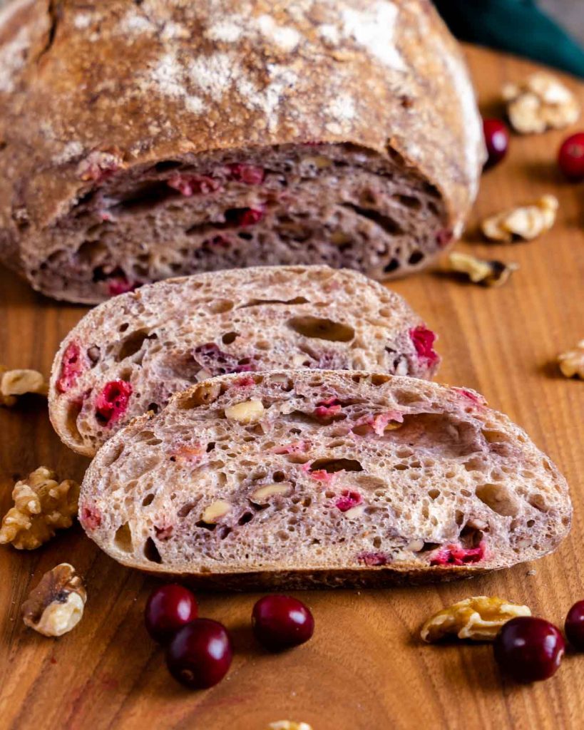 Closeup view of sliced Sourdough Cranberry Walnut Bread with the loaf in the back.