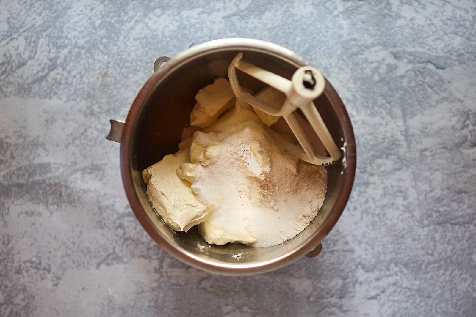 Sugar and cream cheese in a bowl to make Pistachio White Chocolate Cheesecake