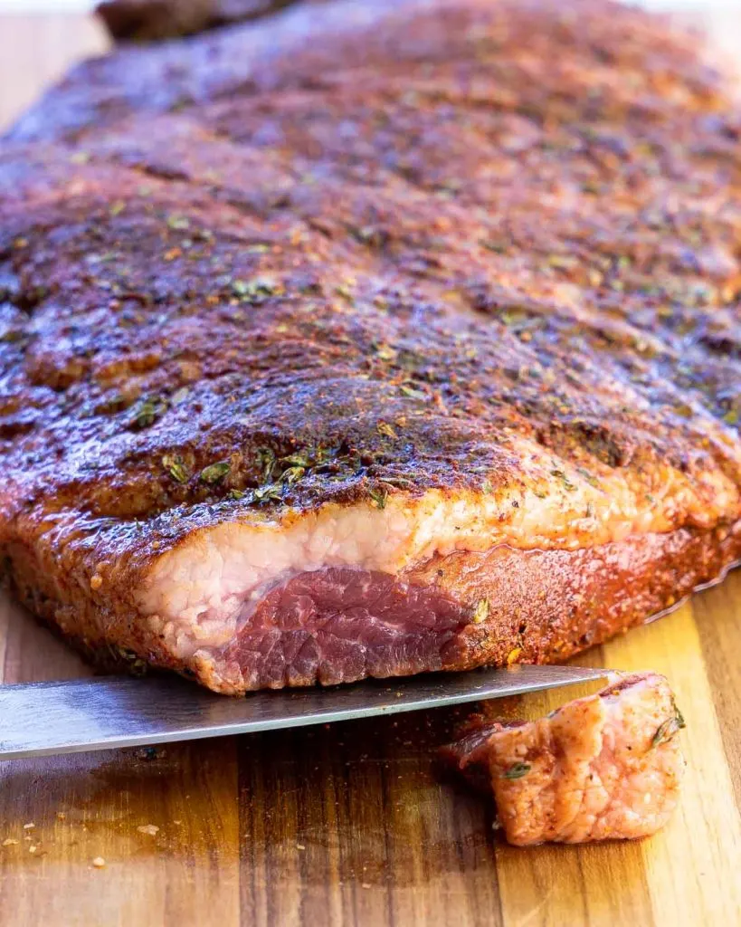 A beef brisket with the tip cut off showing the grain.