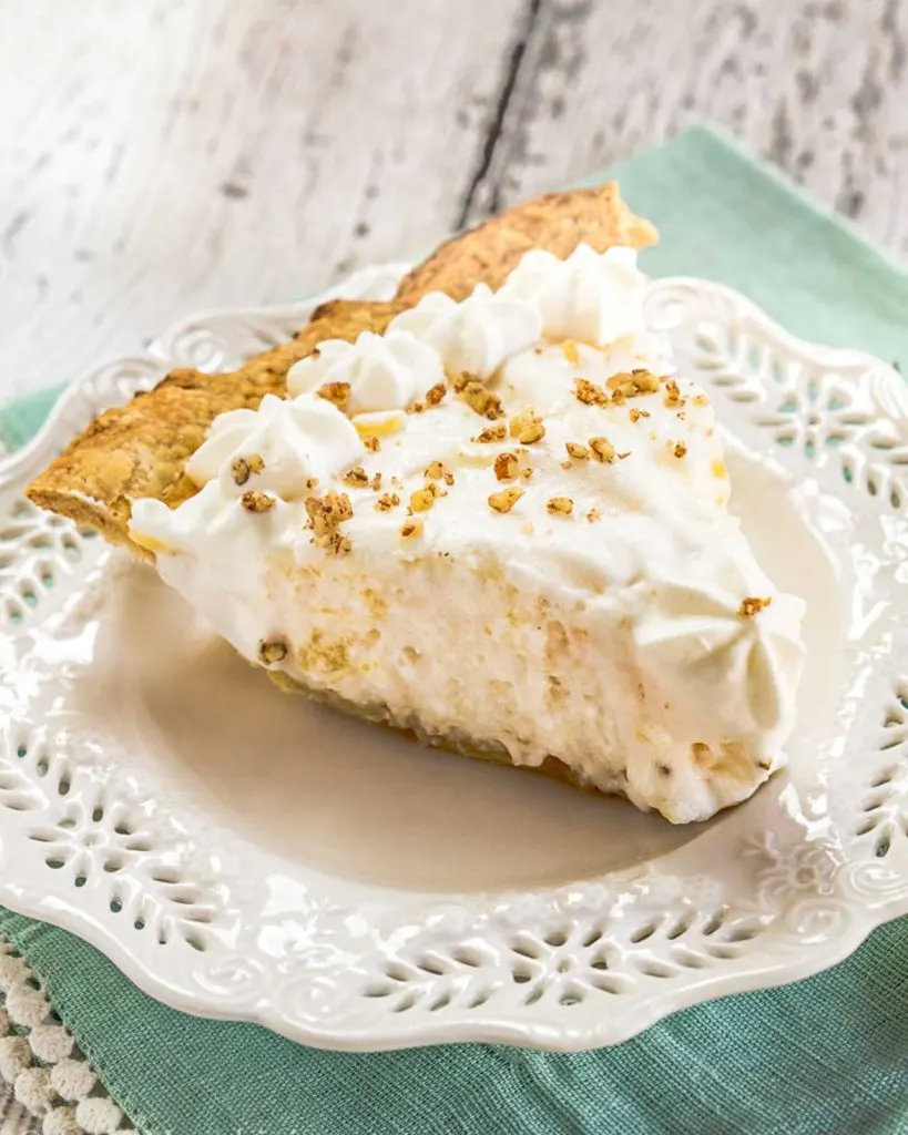 A slice of Angel Food Pie topped with piped whipped topping and crushed pecans.