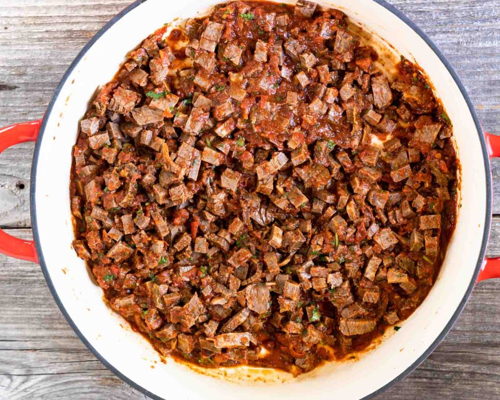 Chopped beef brisket in a pan covered with chipotle sauce.