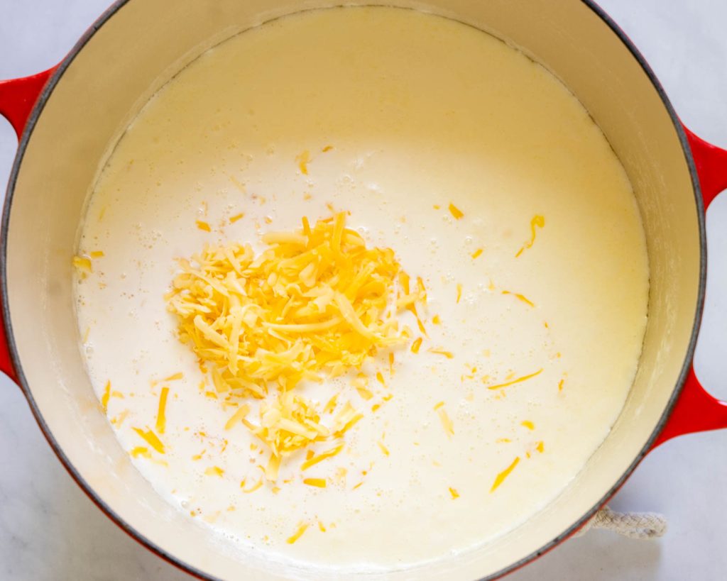 Cheese added to warm cream in a pan.