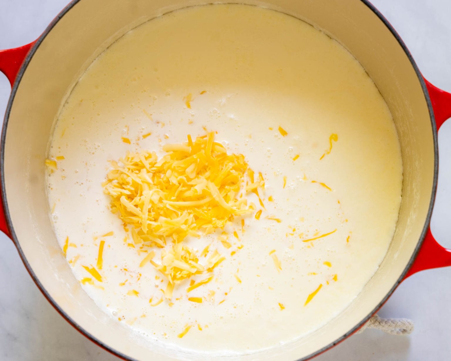 Cheese added to warm cream in a pan.