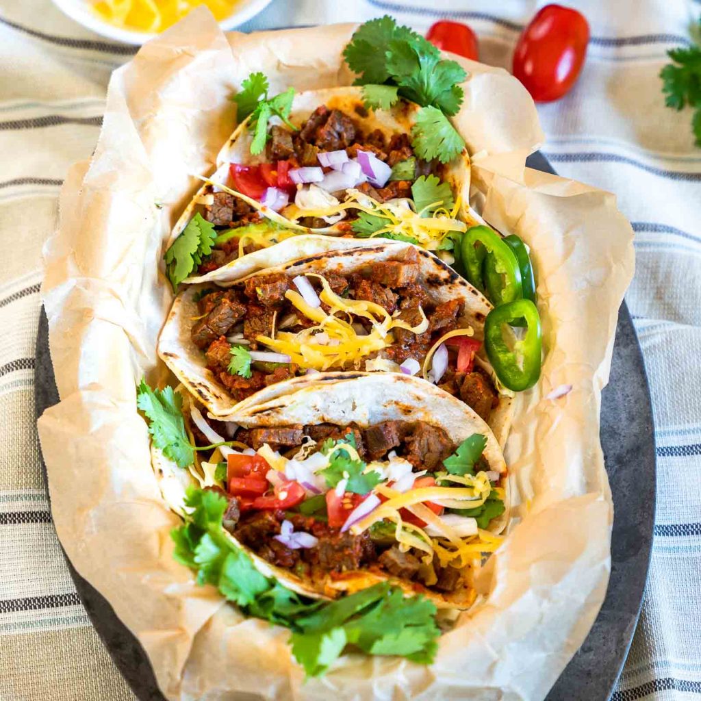 Vertical image of three beef tacos in a basket.