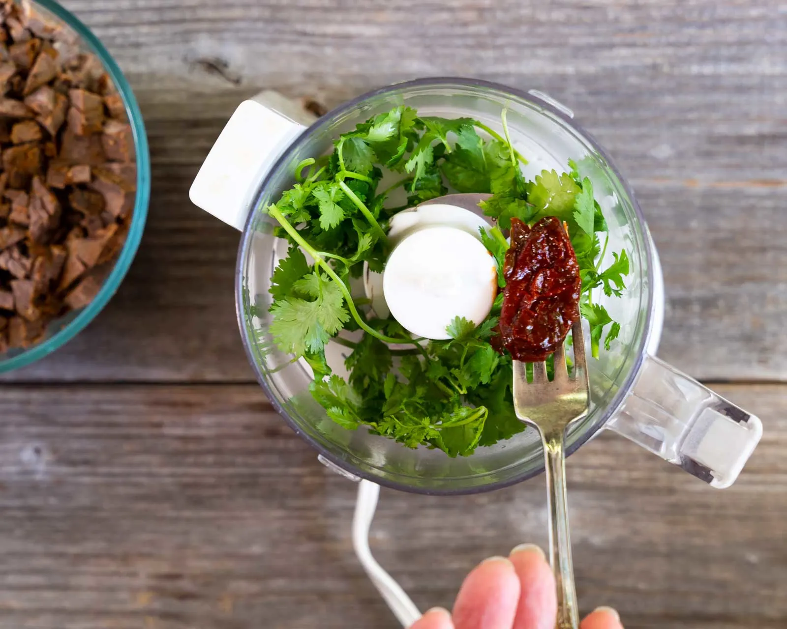 A chipotle chili added to cilantro in a food processor.