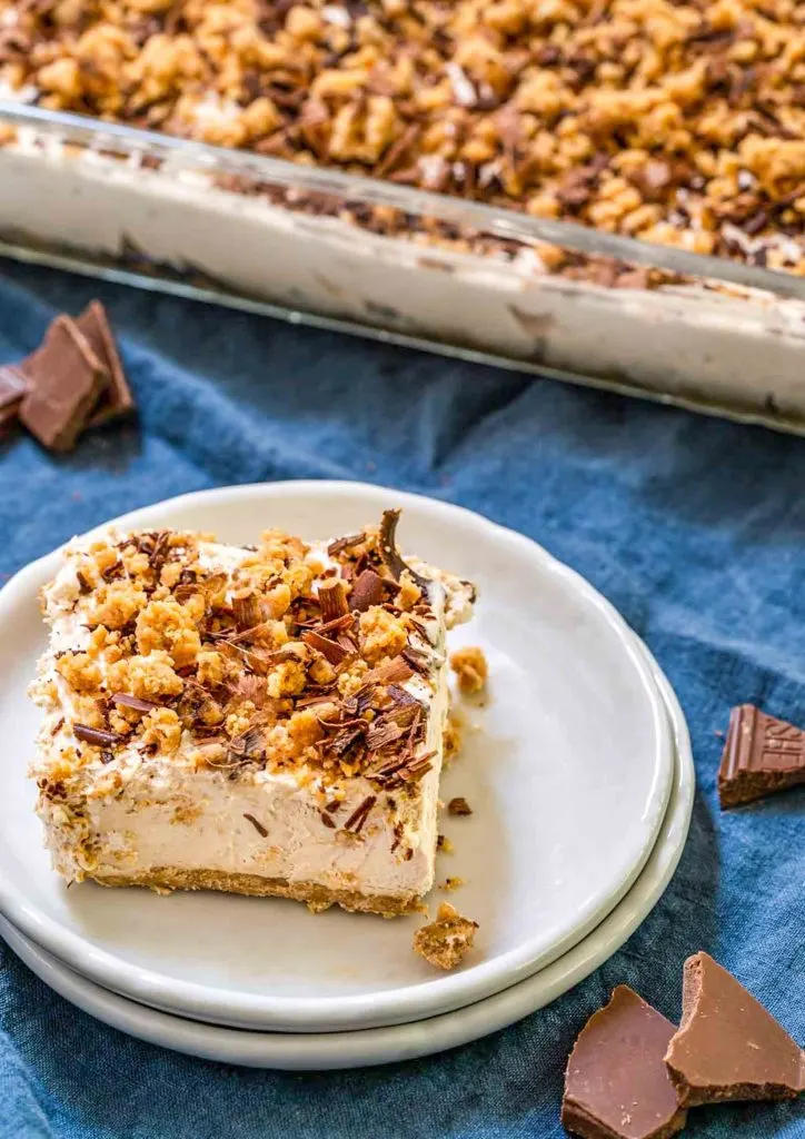 An angled view of sliced peanut butter cheesecake topped with crumble and shaved chocolate.