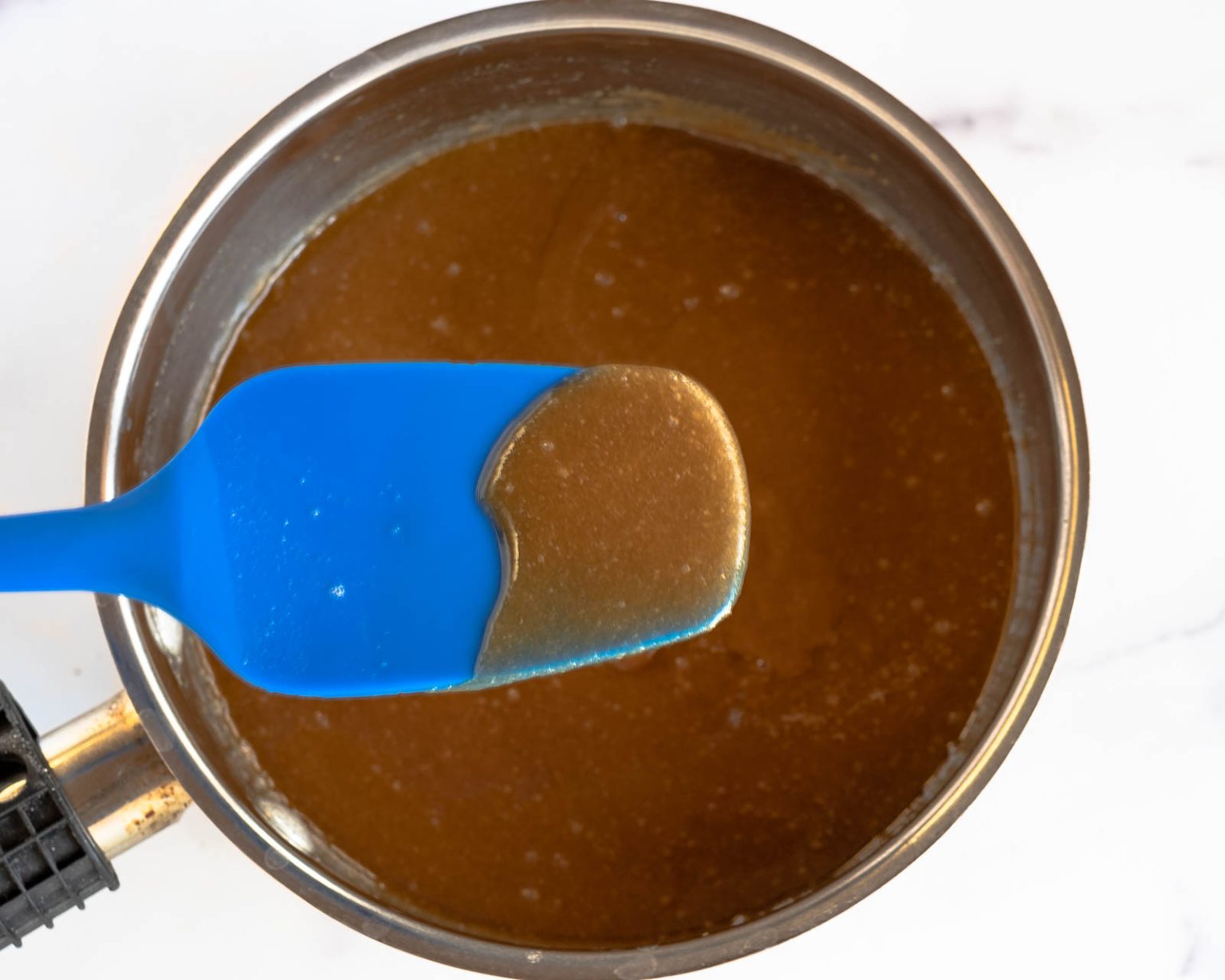 A pan with melted butter and chocolate on a spatula over a saucepan.