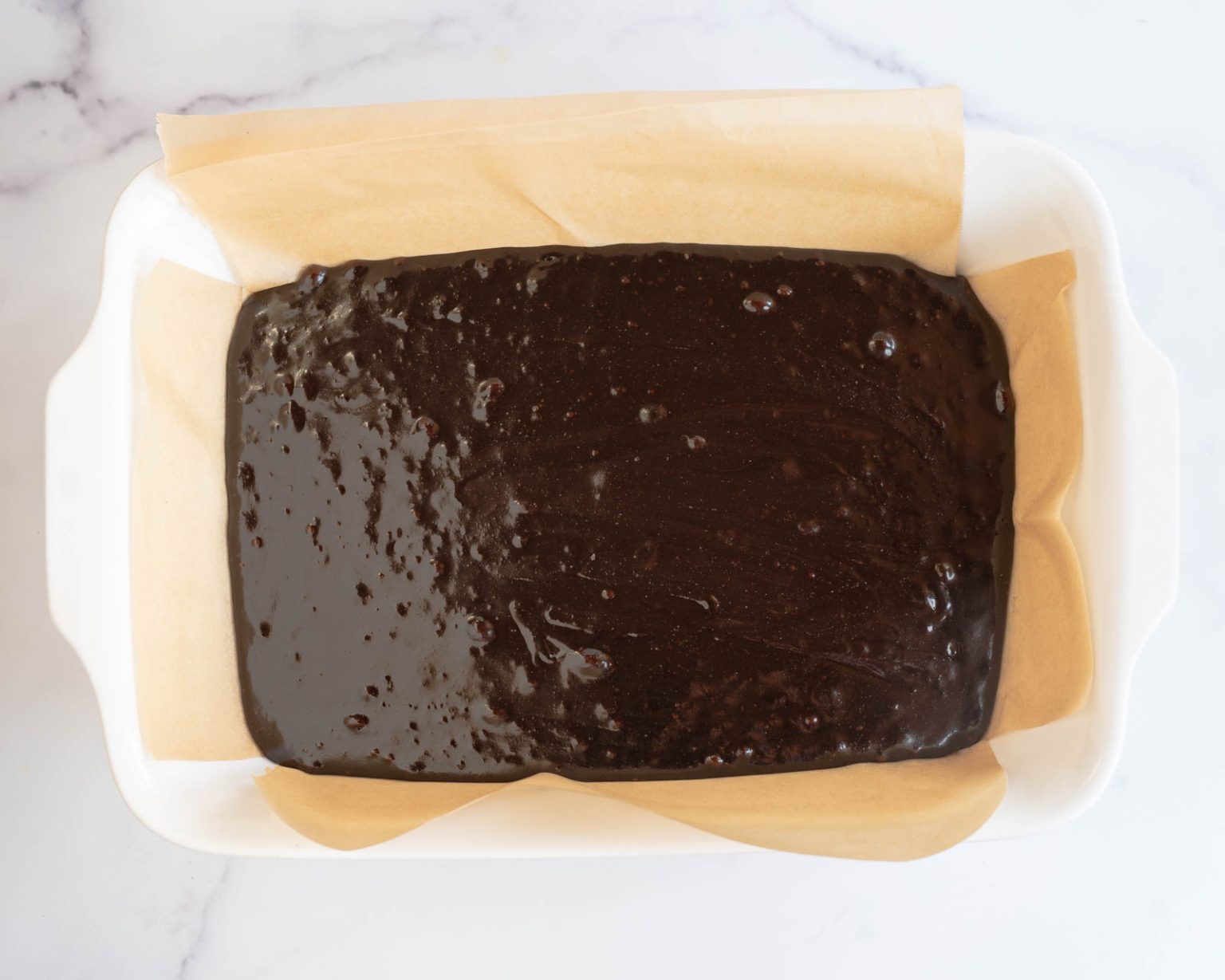 Top down view of dark chocolate brownie batter in a baking dish.
