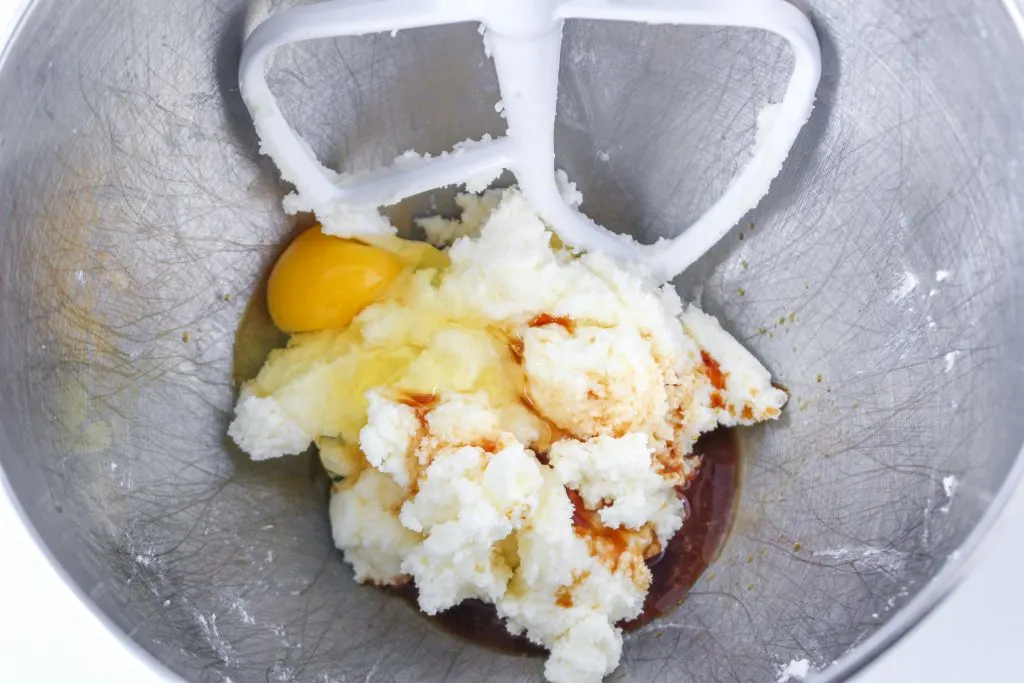 Creaming butter, vanilla, and eggs together in a mixing bowl.