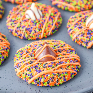 Angled view of a thumbprint cookie covered in sprinkles and topped with a Chocolate Candy Kiss and candy glaze.