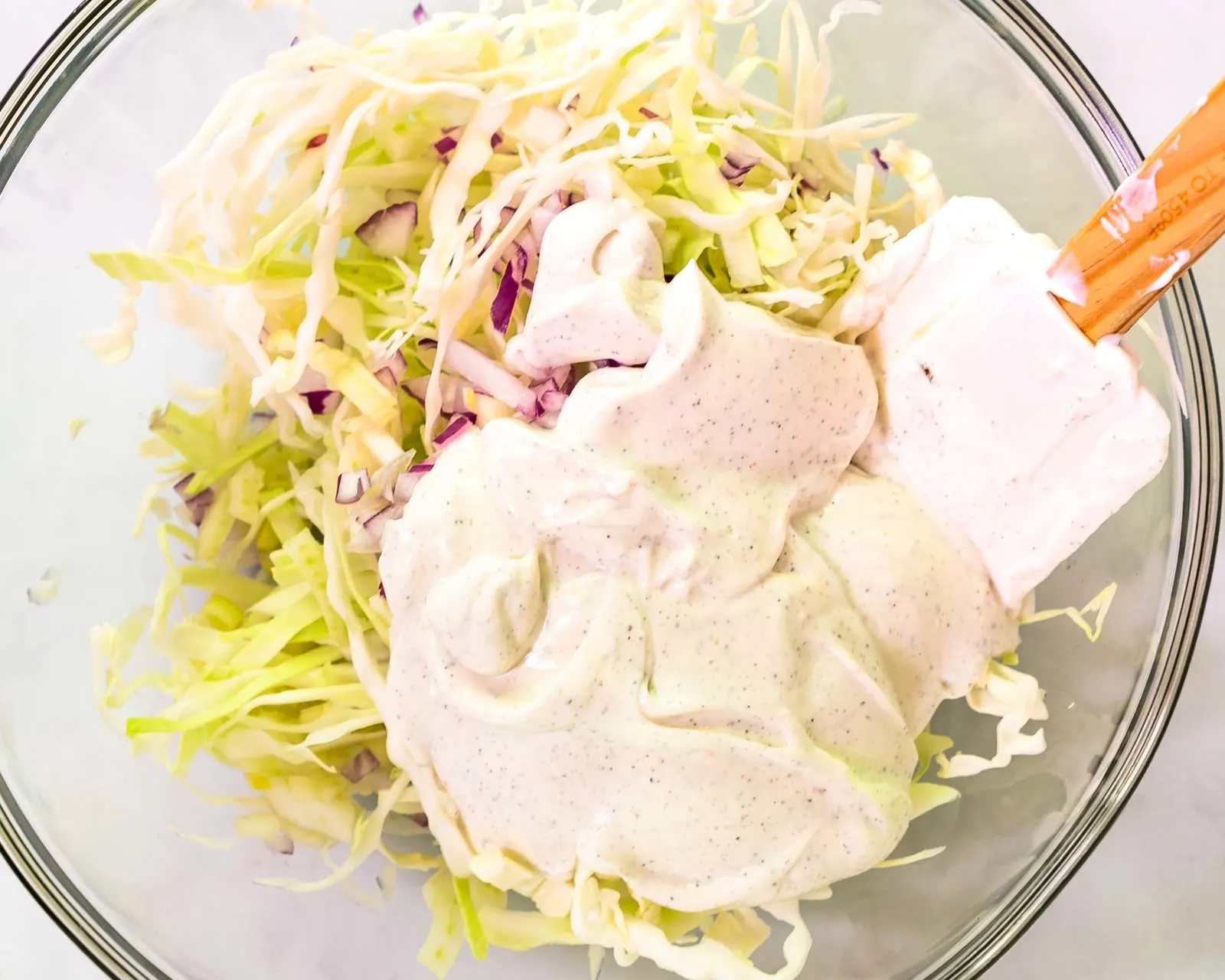 Top down view of shredded cabbage with slaw sauce sitting on top.