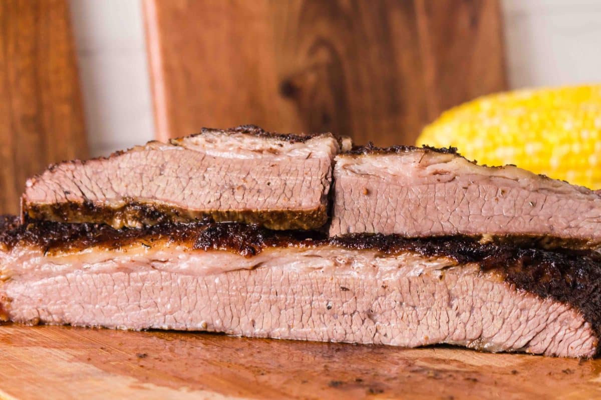 Two large slices of baked brisket sitting on a cutting board. Hostess At Heart
