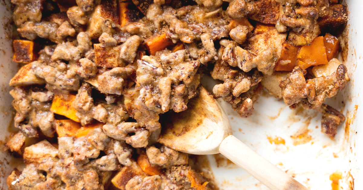 Top down view of a casserole dish filled with baked sweet potate and apples topped with pecan brown sugar topping.