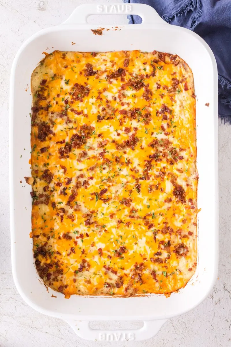 A casserole dish filled with cheese and bacon topped mashed potatoes cassarole.