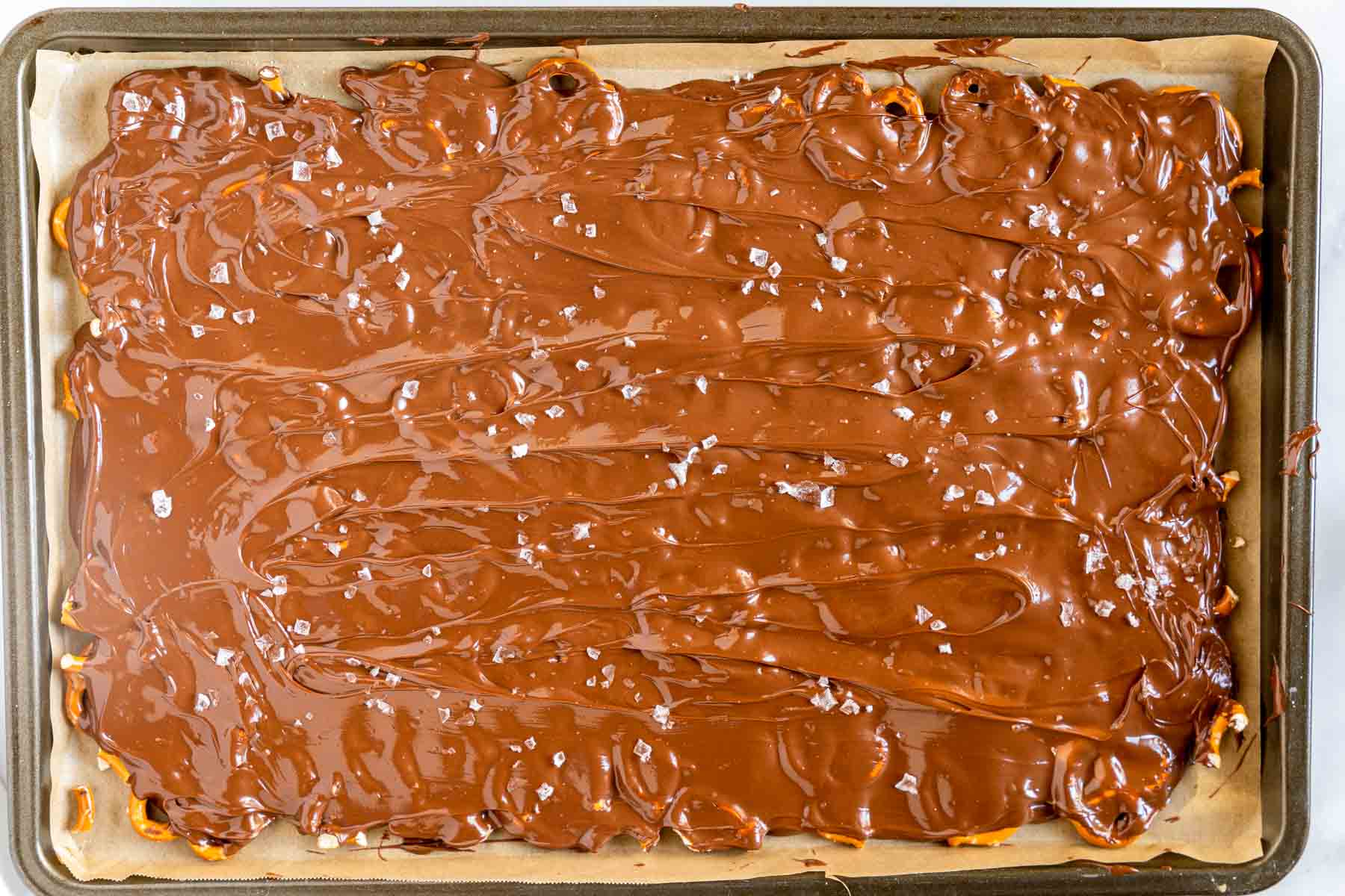 Melted chocolate covering pretzel pieces and sprinkled with flaky sea salt - Hostess At Heart