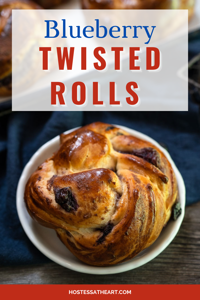 Top down view of a blueberry pastry braided to make a round bread roll. The plate sits on a blue napkin over a wooden background - Hostess At Heart