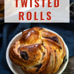 Top down view of a blueberry pastry braided to make a round bread roll. The plate sits on a blue napkin over a wooden background - Hostess At Heart