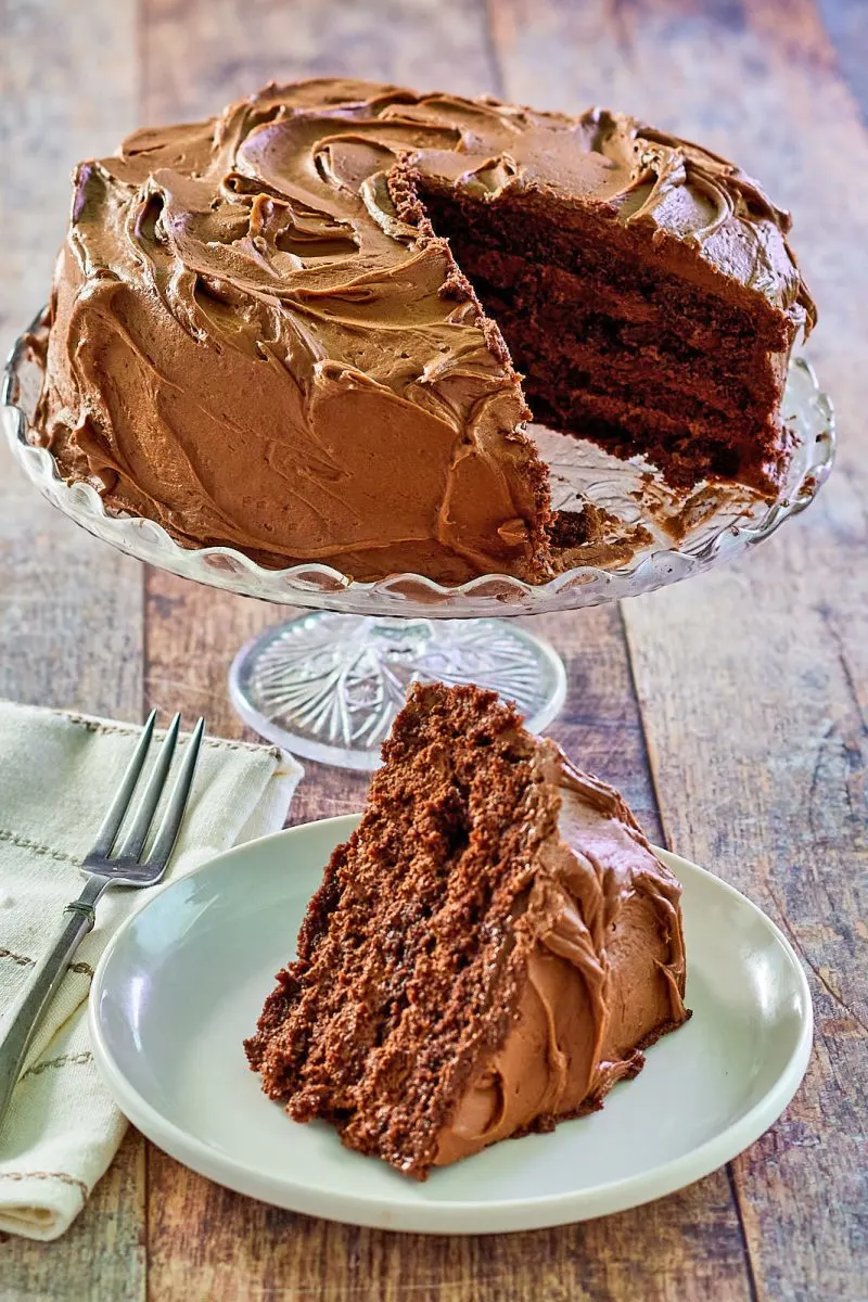 Slice of chocolate cake with layers of creamy chocolate mousse frosted with chocolate buttercream on a plate - Hostess At Heart