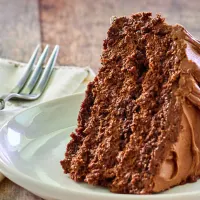 A side view of a slice of mouse cake showing the layers of cake, mouse and frosting on a plate.
