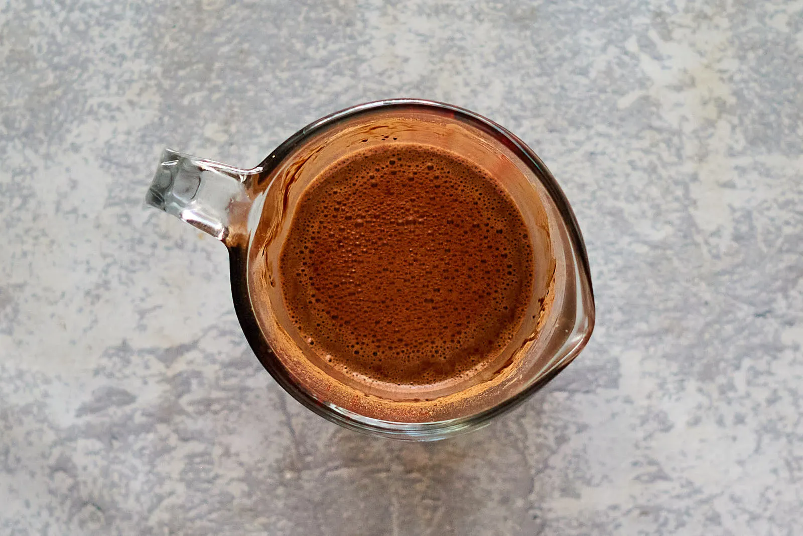 Cocoa and hot water combined together in a measuring cup.