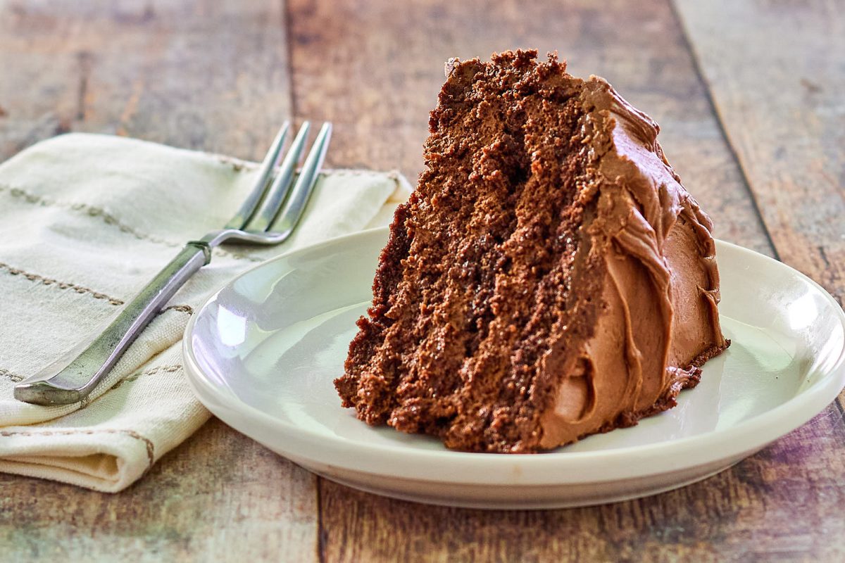 Side view of a slice of a chocolate mousse layer cake on a plate - hostess at heart
