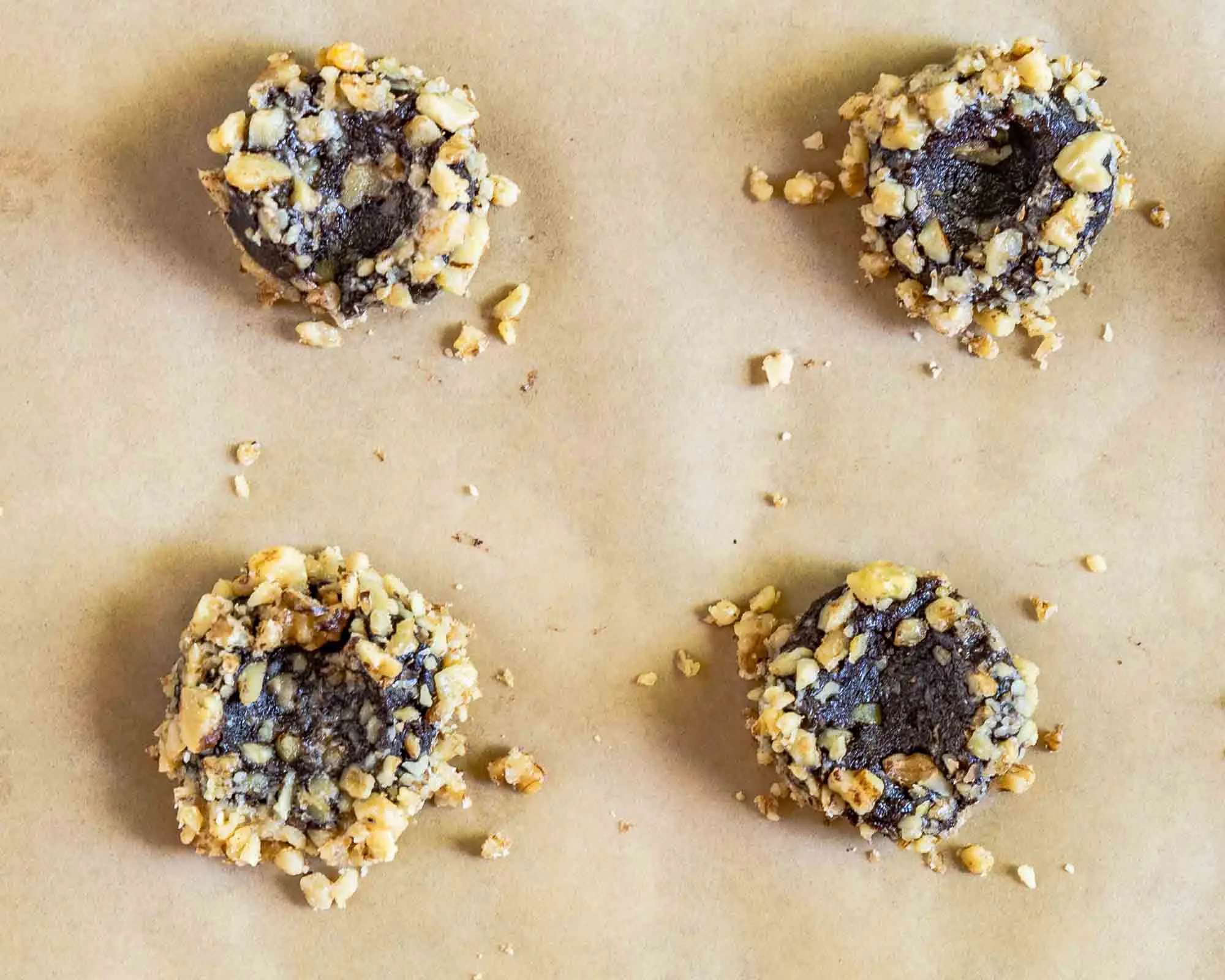 Top down view of indented thumbprint cookies rolled in nuts.