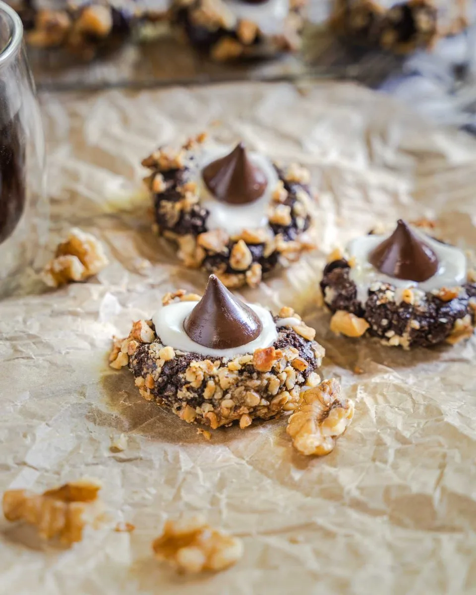 Side view of a cookie rolled in nuts and topped with a chocolate chany kiss.