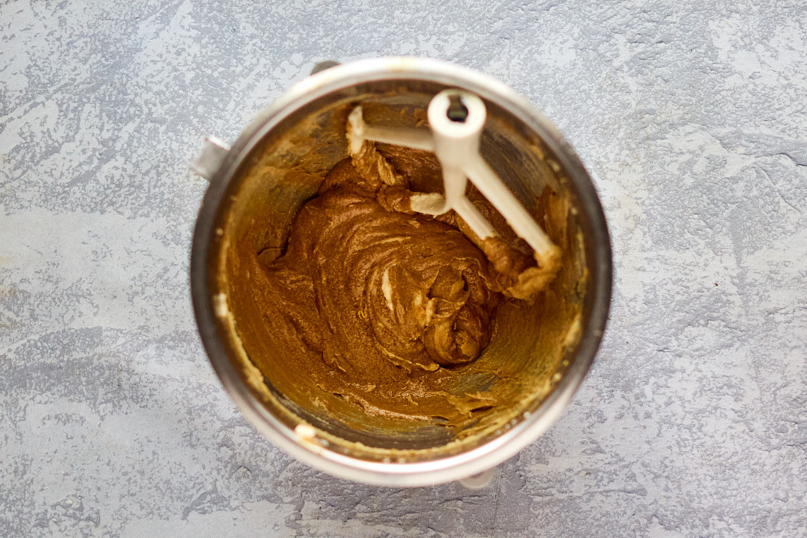 A mixing bowl filled with wet gingerbread batter ingredients creamed together.