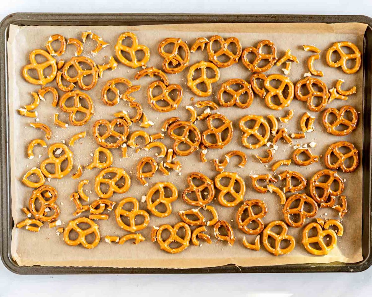 A sheet pan covered with parchment paper topped with mini pretzels waiting to be covered with chocolate - hostess at heart