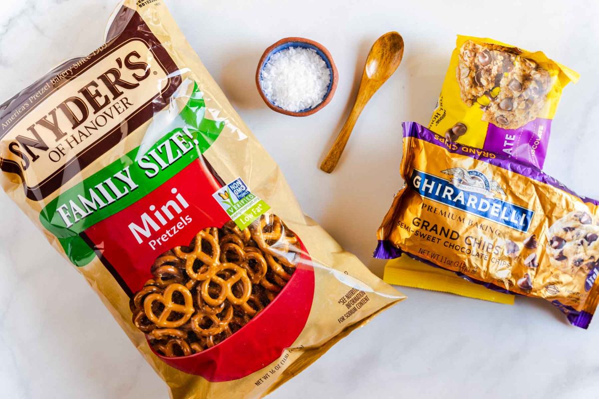 Ingredients used to make chocolate bark covered pretzels including mini pretzels, sea salt, and chocolate chips.