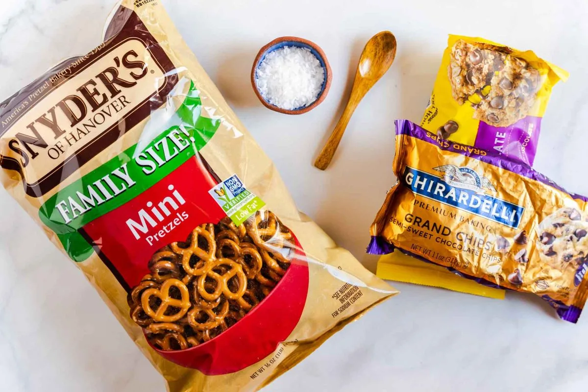 Ingredients used to make chocolate bark covered pretzels including mini pretzels, sea salt, and chocolate chips.