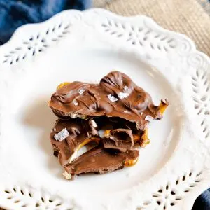 a white plate containing pieces of chocolate pretzel bark sprinkled with sea salt - hostess at heart