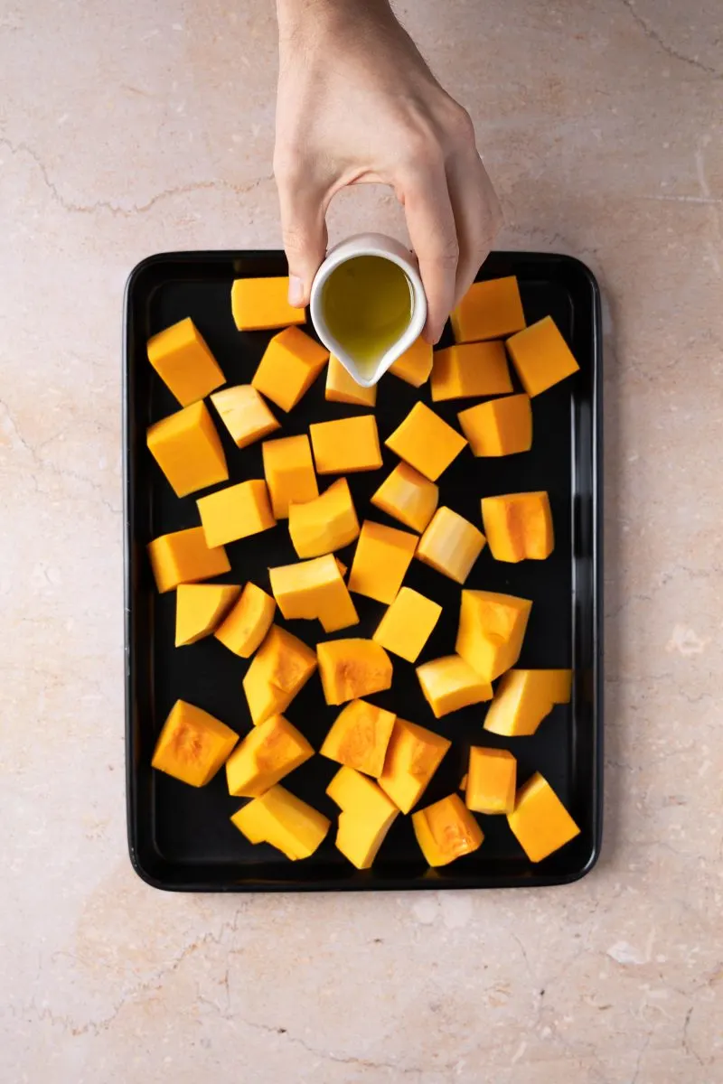 Cubed pieces of raw pumpkin drizzled with olive oil