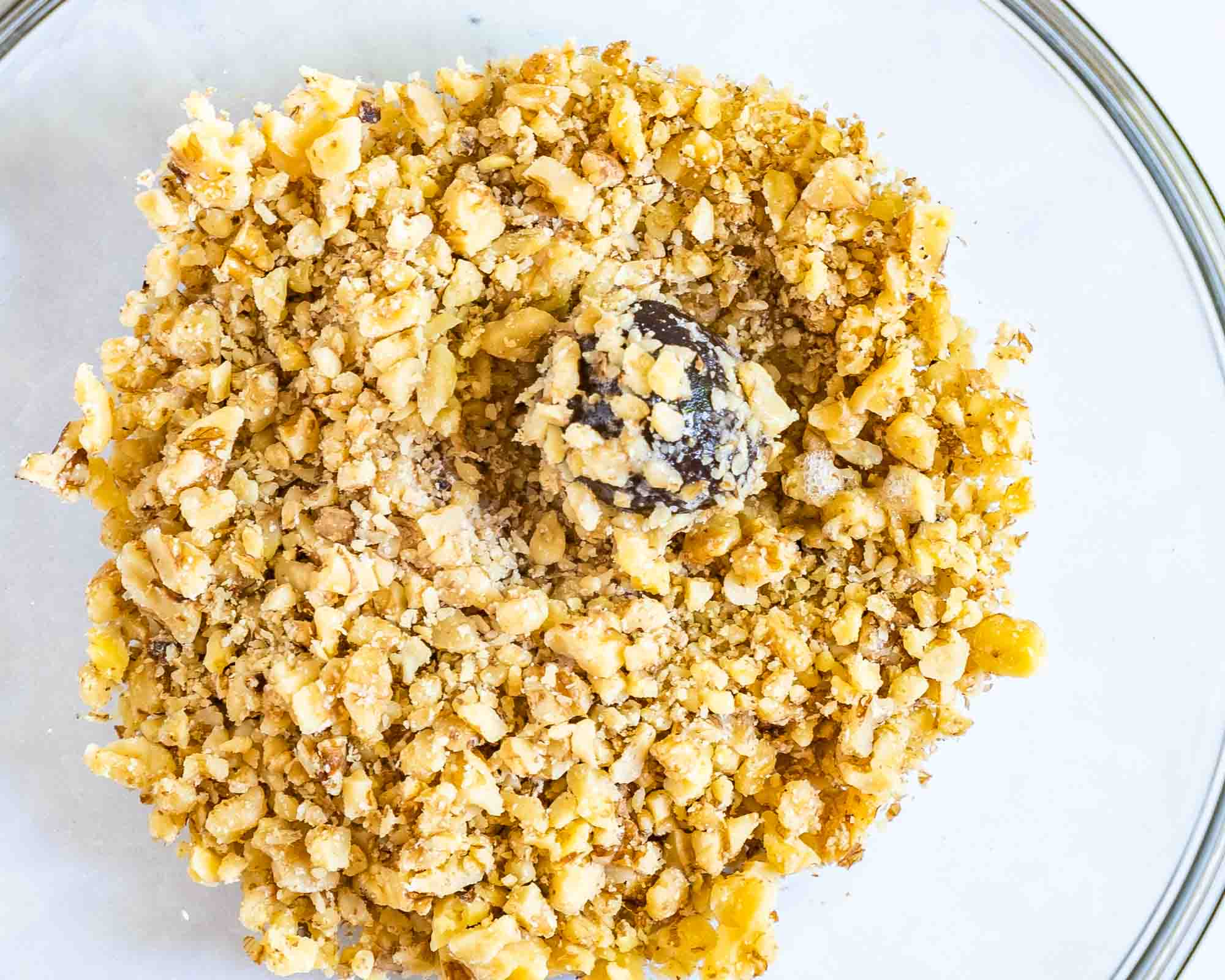 Ball of Chocolate thumbprint cookie dough rolled in crushed nuts.