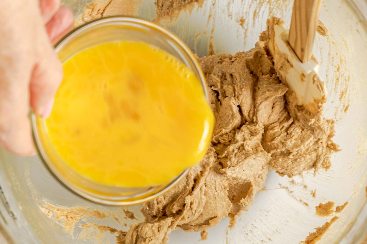 Beaten egg being added to oatmeal cookie dough.