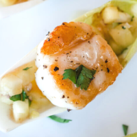A seared scallop sitting on top of pineapple salsa inside an endive leaf. - hostess at heart