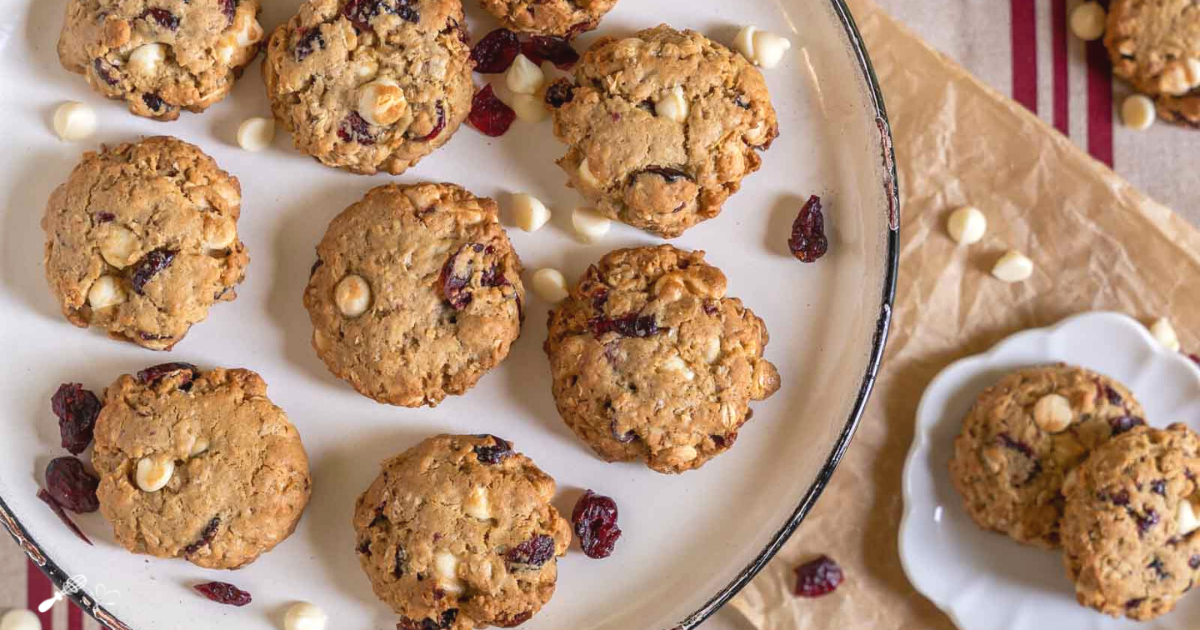 Top down view of white chocolate cranberry oatmeal cookies sitting on a white plate over parchment paper.